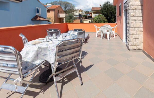 Una terraza con una mesa lista para comer, sillas exteriores y una silla de metal con una mesa unida.