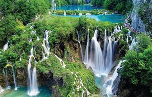 A lush, multi-tiered waterfall surrounded by dense greenery.