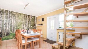 A dining area with a table set for four, a wooden bench, and a view of a forest through a window. - Nice Home in Licko Lesce With 2 Bedrooms and Wifi (Otocac)