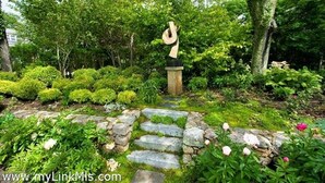 Un giardino con un sentiero in pietra che conduce a una scultura.