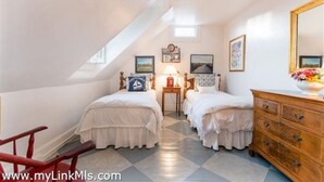 Una camera da letto con due letti, una cassettiera in legno, uno specchio e un piccolo tavolo con una lampada.