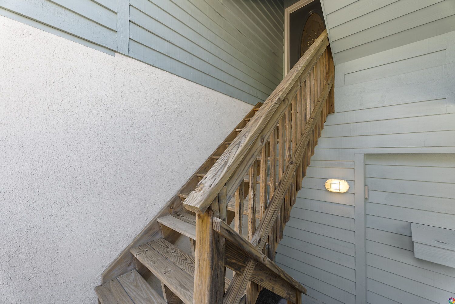 A wooden staircase with a light fixture on the wall.
