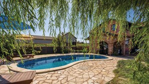 A swimming pool with a stone patio, surrounded by a brick building and a wooden deck. - Stunning Home in Ozalj With 5 Bedrooms, Wifi and Outdoor Swimming Pool (Karlovac)