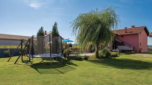 A backyard with a trampoline, a swing set, a pool, and a large tree. - Stunning Home in Ozalj With 5 Bedrooms, Wifi and Outdoor Swimming Pool (Karlovac)