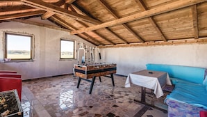 A rustic room with a wooden ceiling, a foosball table, a blue sofa, and a small table with a white tablecloth. - Stunning Home in Ozalj With 5 Bedrooms, Wifi and Outdoor Swimming Pool (Karlovac)