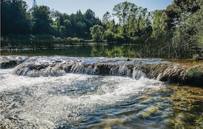A waterfall in a forested area with clear water and surrounding greenery.