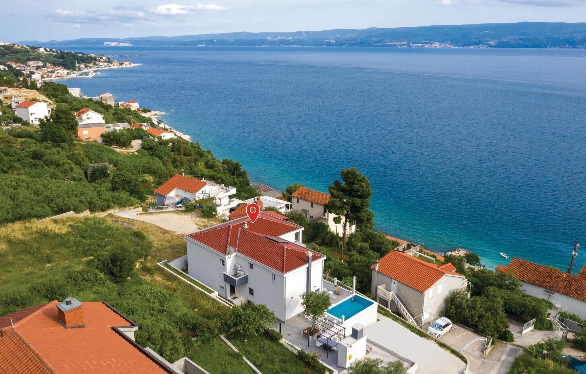 A coastal residential area with houses, a swimming pool, and a view of the sea.