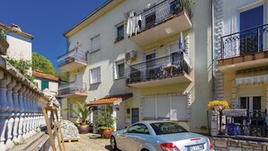 A residential building with multiple balconies, a parked car, and potted plants. - Amazing Home in Opatija With Wifi and 0 Bedrooms (Opatija)