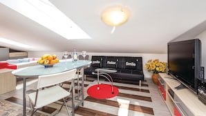 A modern kitchen with a dining area, a black sofa with 'Smile Relax Smile' cushions, a TV, and a fruit bowl on the table. - Amazing Home in Opatija With Wifi and 0 Bedrooms (Opatija)