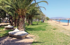 A beachside walkway lined with palm trees and a stone bench. - Awesome Home in Nea Makri With Wifi and 3 Bedrooms (Marathon)