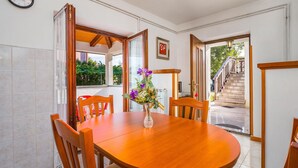 A dining area with a wooden table and chairs, a vase with flowers, and a view of a staircase leading outside. - Beautiful Home in Kapelica With Wifi and 2 Bedrooms (Labin)