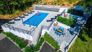 An aerial view of a rooftop pool area with a swimming pool, sun loungers, and outdoor seating. - Awesome Apartment in Kostrena With 3 Bedrooms, Wifi and Outdoor Swimming Pool (Kostrena)