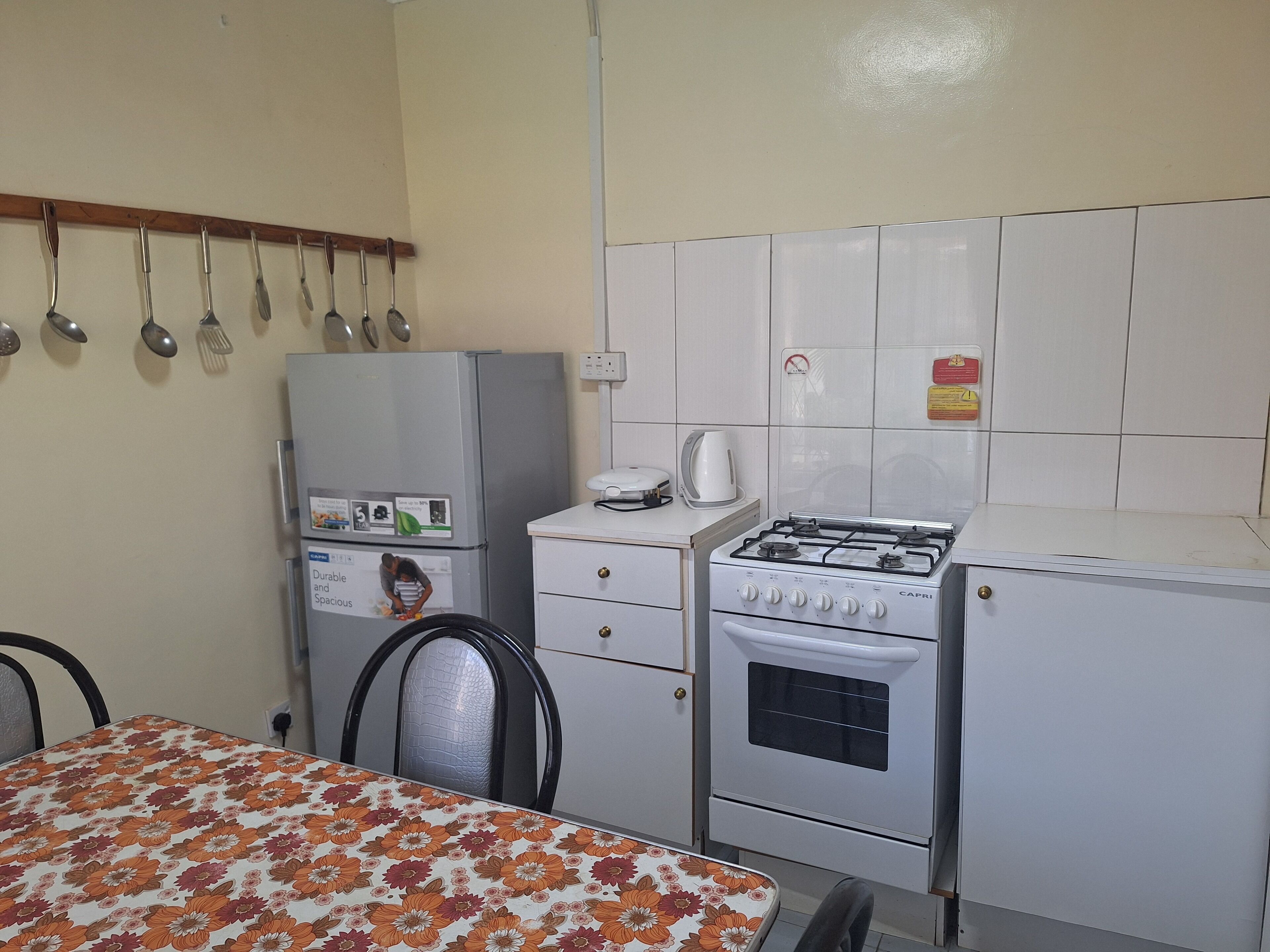 A compact kitchen with a refrigerator, stove, and a dining table with chairs.