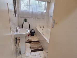 Une salle de bain équipée d’un lavabo, de toilettes, d’une baignoire et d’une fenêtre donnant sur un beau paysage.