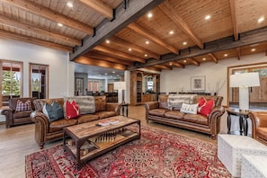 A spacious living room with leather sofas, a coffee table, and a patterned rug.