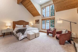A bedroom with a large bed, a nightstand, a chair, and a floor lamp.
