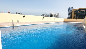 Una piscina sul tetto con acqua cristallina, circondata da grattacieli.
