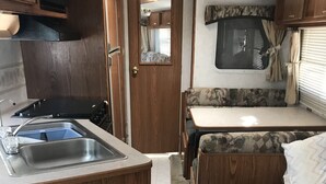 Een kleine keuken voor een camper, met een spoelbak, fornuis en magnetron.