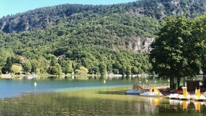 A calm lake with boats docked, surrounded by lush green hills. - Atypical chalet, calm nature and river (Hautecourt-Romanèche)