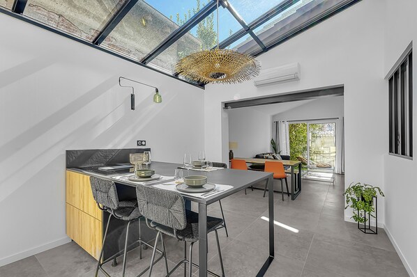 A modern kitchen with a dining area, a built-in stove, and a large window.
