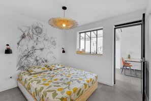 A modern bedroom with a bed, a wall-mounted lamp, and a window.