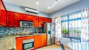 A kitchen with red cabinets, a stainless steel refrigerator, and a microwave. - Cozy Oceanview Condo w/ Swimming Pool Near the Beach (Playa Flamingo)