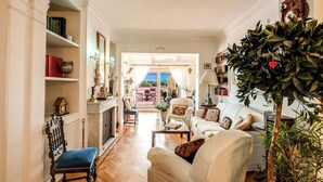 Ein geräumiges Wohnzimmer mit Kamin, einer großen Pflanze und Blick ins Freie.