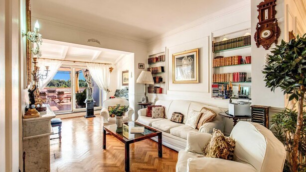 Ein großzügiges Wohnzimmer mit einem weißen Sofa, einem Couchtisch und einem Bücherregal voller Bücher.