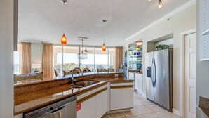 A modern kitchen with granite countertops, stainless steel appliances, and pendant lighting.