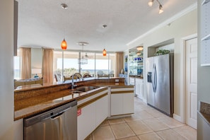 A modern kitchen with granite countertops, stainless steel appliances, and pendant lighting.