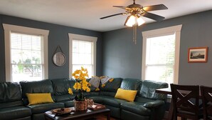 A living room with a sectional sofa, a coffee table with board games, and a dining area with chairs.