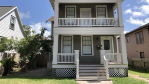 A two-story house with a front porch, a mailbox, and a number 911 sign.