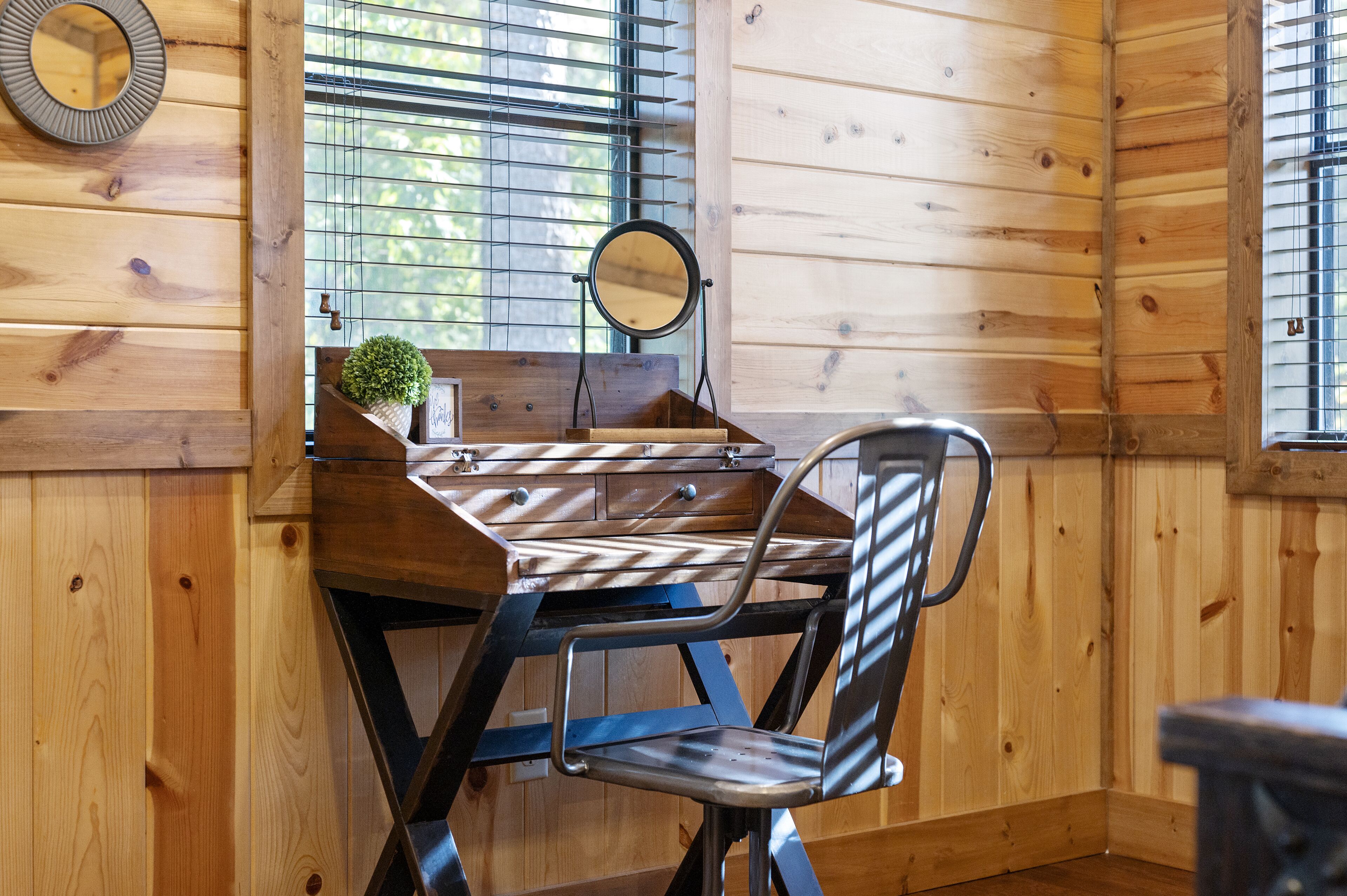 Ein Holzblockhaus-Interieur mit Schreibtisch, Stuhl und einem kleinen, runden Spiegel.