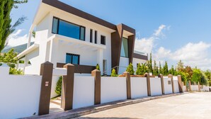 A modern two-story house with a white exterior, large windows, and a brown accent wall.