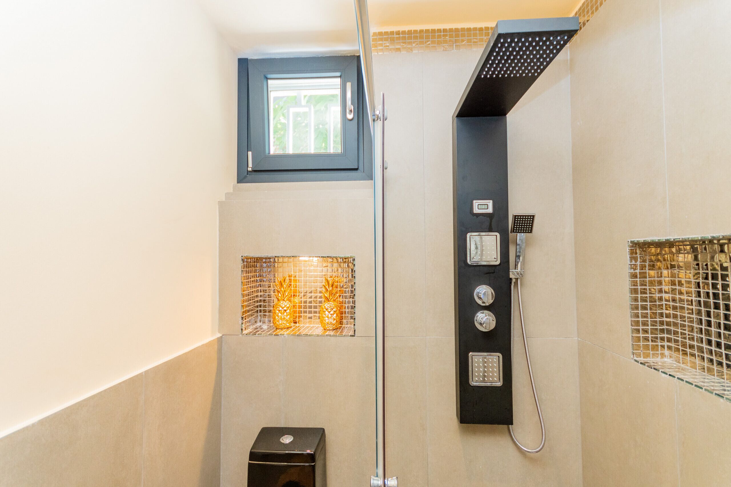 A modern shower with a control panel, a small window, and a decorative shelf with pineapples.
