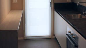 Una cocina moderna con encimera negra, pileta de acero inoxidable y una puerta corredera de vidrio.