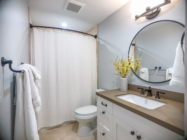 Un baño con inodoro, lavamanos, espejo y toallero.