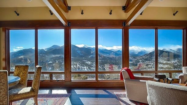 A room with large windows offering a mountain view. There are several chairs and a table. - Stewart Highlands Vacation Home at Windcliff (Estes Park)