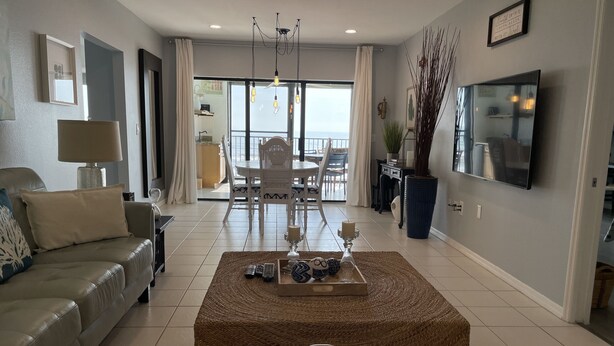 Un salon moderne avec un canapé, une table basse et un téléviseur. Il y a un balcon avec vue.