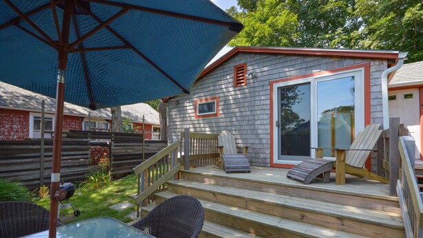 A wooden deck with outdoor furniture, a barbecue grill, and a covered patio area.