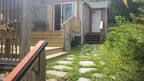 A wooden deck leading to a house with a sliding glass door and a small porch.