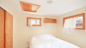 A bedroom with a bed, wooden ceiling, and windows.