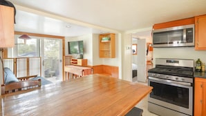 A kitchen with a wooden table, a microwave, and a stove.