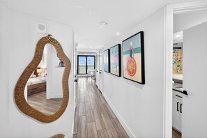 Ein Flur mit einem großen Spiegel, gerahmten Kunstwerken und Blick auf einen Balkon.
