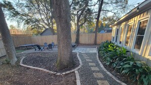 Un jardin avec un chemin de pierres, un arbre et du mobilier d’extérieur.