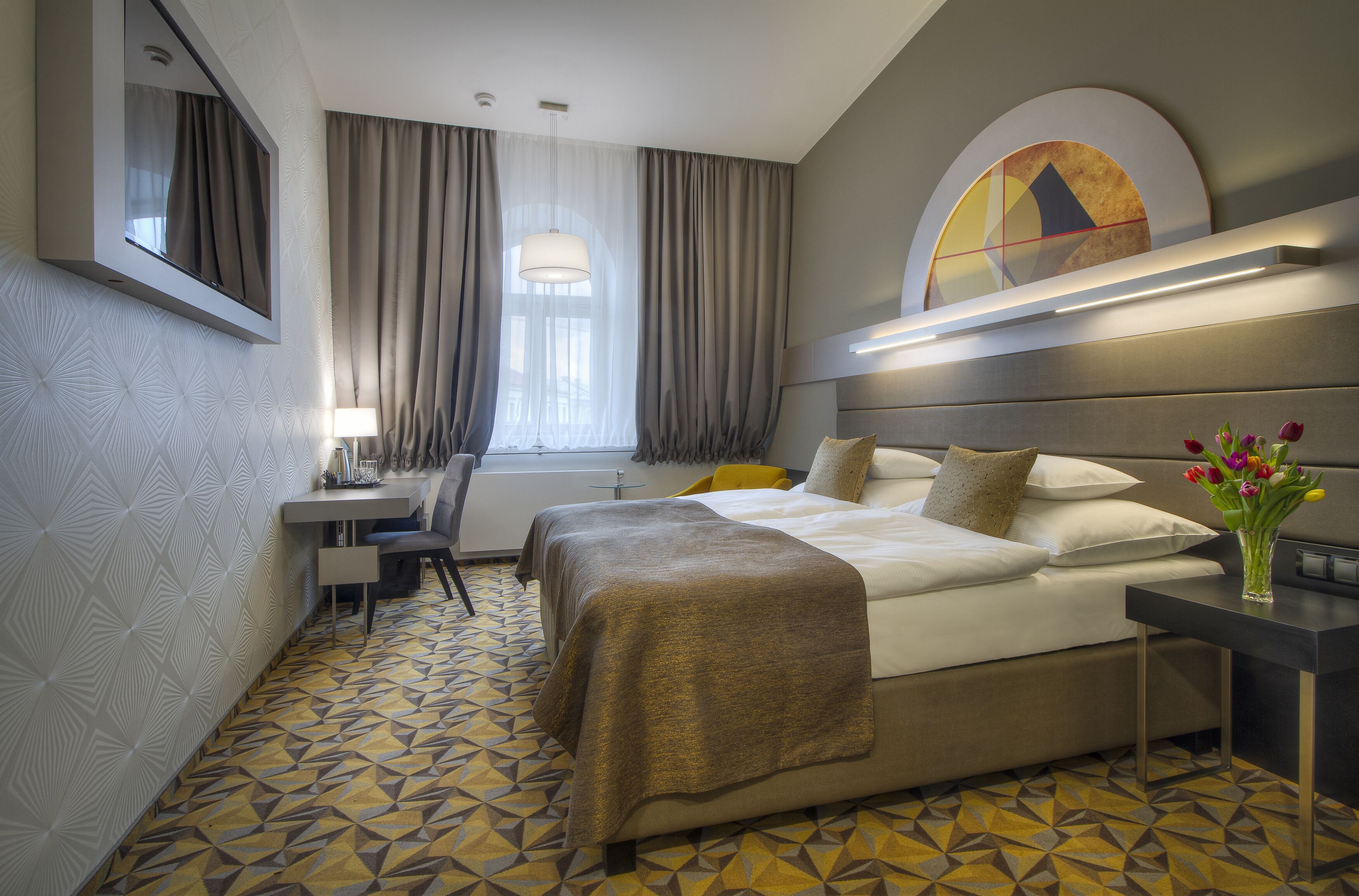 Una habitación de hotel con cama, mesita de noche, escritorio y silla.