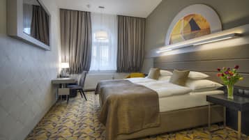 Una habitación de hotel con cama, mesita de noche, escritorio y silla.