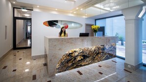 A modern reception area with a marble counter, a large window with a view, and a chandelier. - Hotel Essence  (Prague)