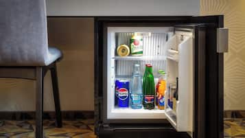 Un mini refrigerador lleno de bebidas, incluyendo una lata de Pilsner, Pepsi, Aquafina y una botella de Matton.