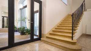 A staircase with beige steps and black railings, leading to an upper floor. - Hotel Essence  (Prague)